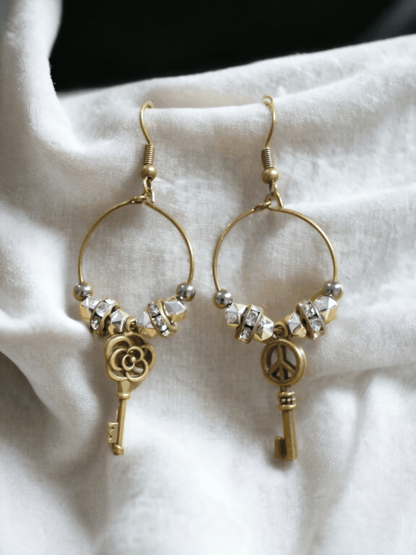 Unique earrings with bronze-colored hoops, round beads, rhinestone rounds, and key-shaped pendants from Zee’s Pieces, featuring distinct key designs, perfect for adding charm and individuality to any outfit, ideal for both casual and formal occasions. Only $15.00. 