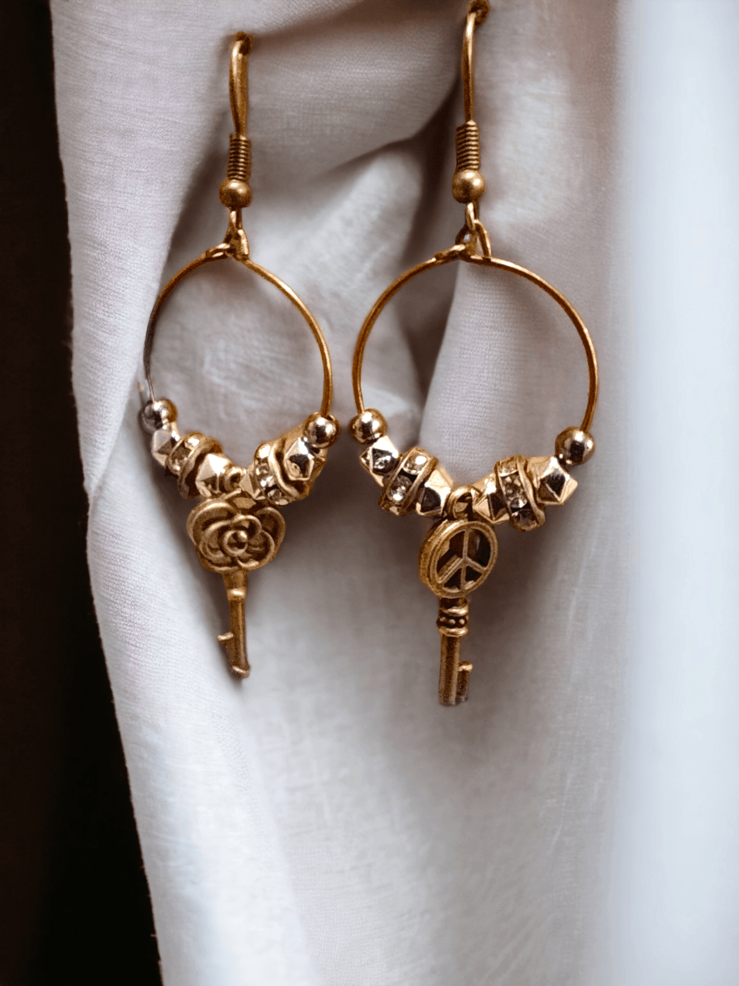 Unique earrings with bronze-colored hoops, round beads, rhinestone rounds, and key-shaped pendants from Zee’s Pieces, featuring distinct key designs, perfect for adding charm and individuality to any outfit, ideal for both casual and formal occasions. Only $15.00. 