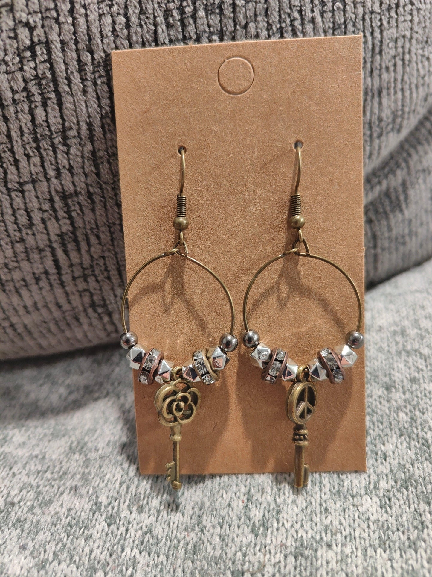 Unique earrings with bronze-colored hoops, round beads, rhinestone rounds, and key-shaped pendants from Zee’s Pieces, featuring distinct key designs, perfect for adding charm and individuality to any outfit, ideal for both casual and formal occasions. Only $15.00. 