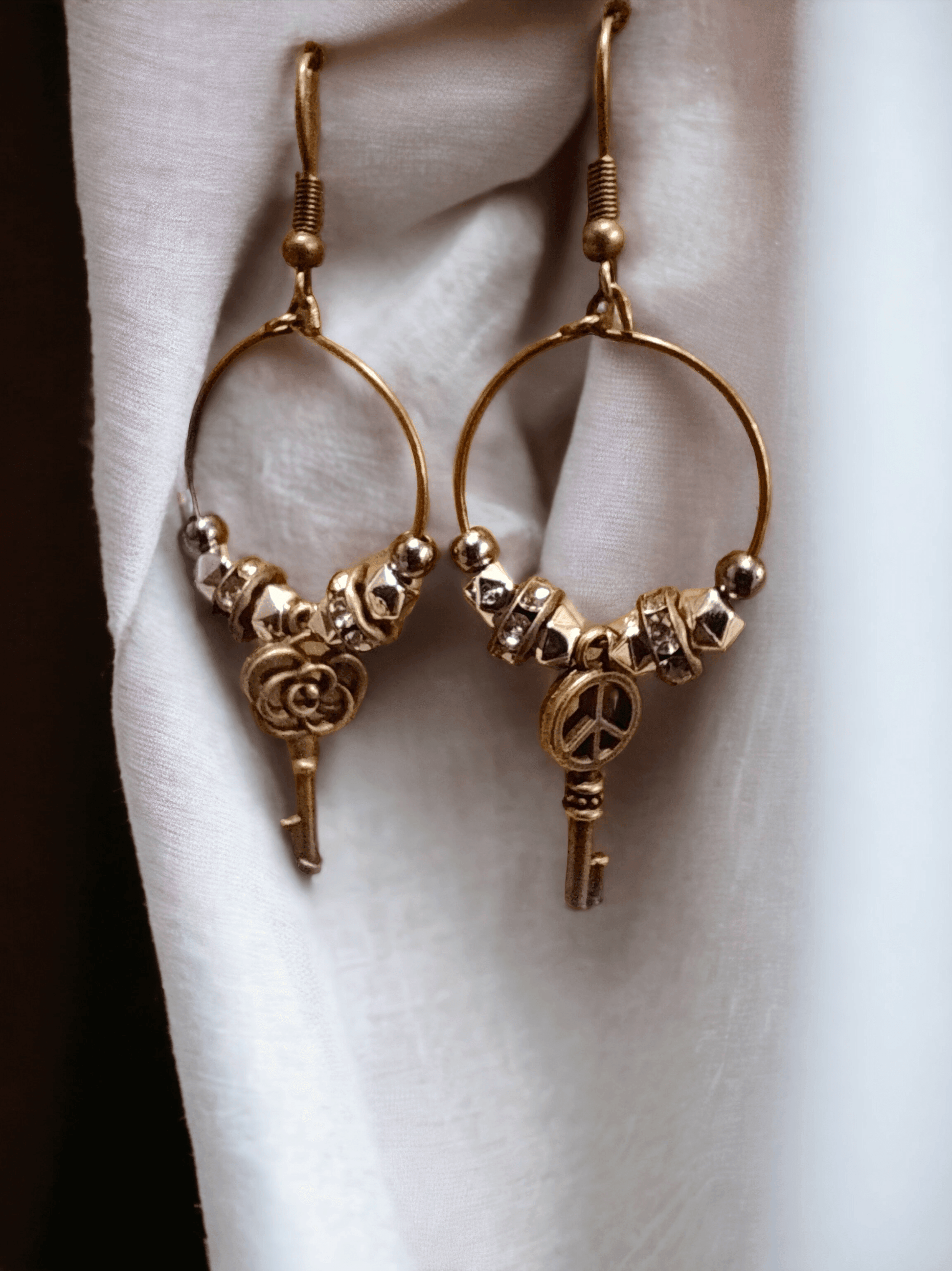 Unique earrings with bronze-colored hoops, round beads, rhinestone rounds, and key-shaped pendants from Zee’s Pieces, featuring distinct key designs, perfect for adding charm and individuality to any outfit, ideal for both casual and formal occasions. Only $15.00. 