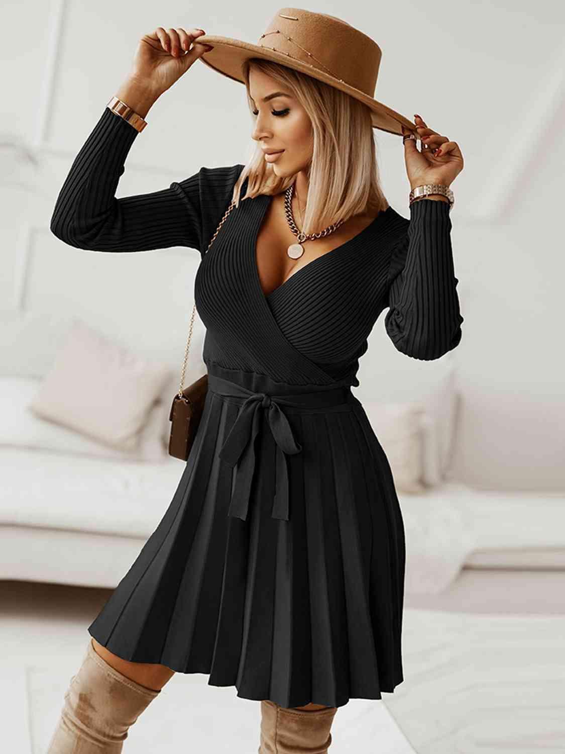 Surplice Neck Tie Front Pleated Sweater Dress - Zee's Pieces. Woman wearing Surplice Neck Tie Front Pleated Sweater Dress, fitted ribbed top, long sleeves, pleated skirt, stylish V-shaped neckline, cozy and chic fall and winter fashion. Army Green, Black, Charcoal Gray, and Khaki colors available. 